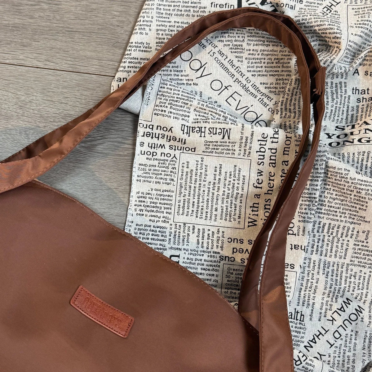 Brown leather bag with a strap on a newspaper background