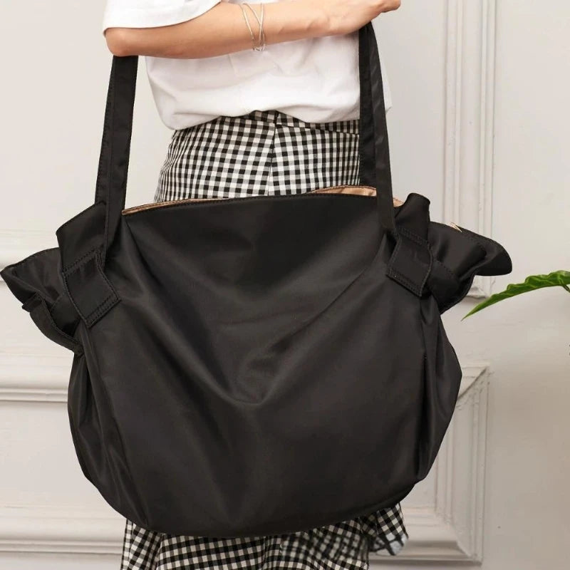 Person holding a black shoulder bag with a white background