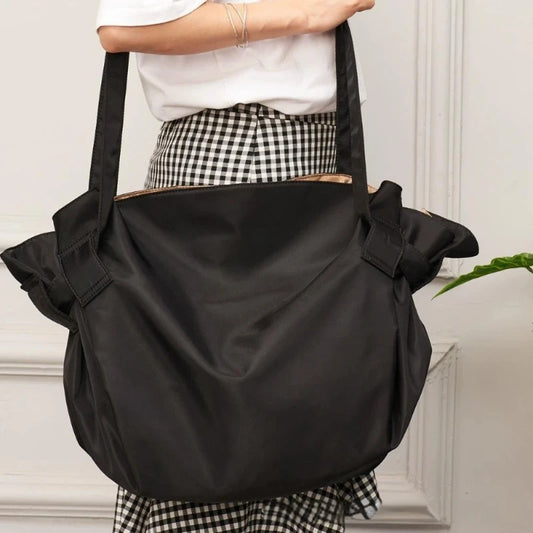 Person holding a black shoulder bag with a white background