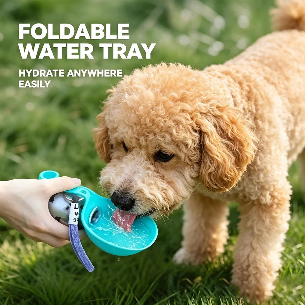 A small tan dog drinking from a bright turquoise foldable water tray held by a person outdoors on grass, with text reading 'FOLDABLE WATER TRAY' and 'HYDRATE ANYWHERE EASILY'.
