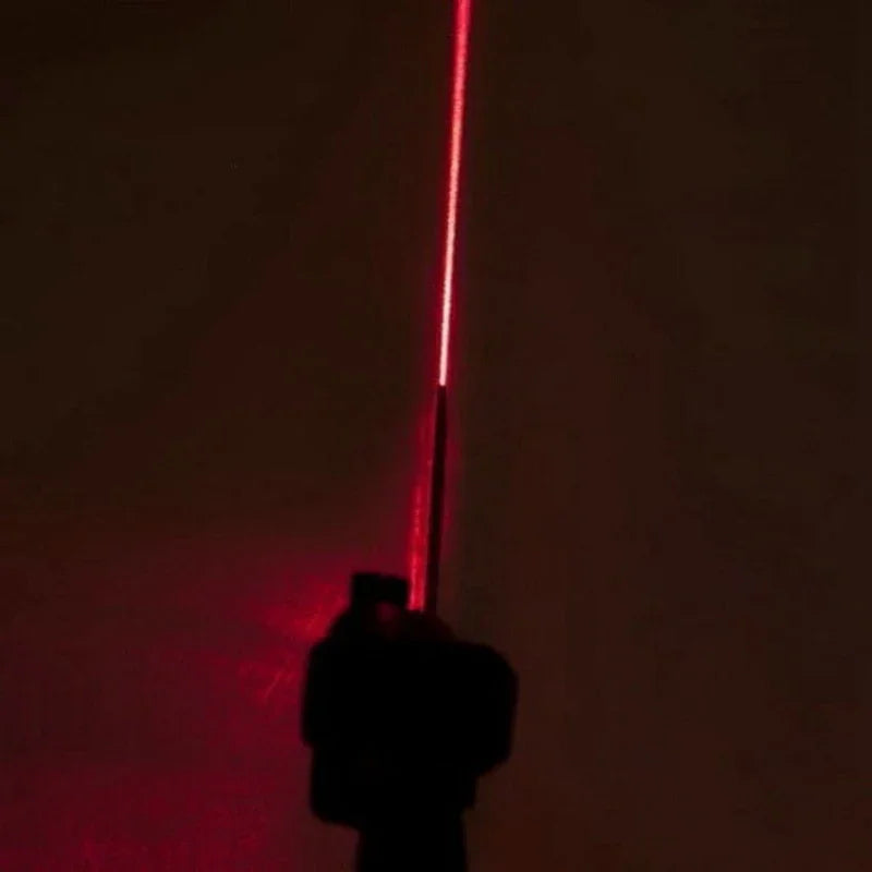 Red laser pointer held against a dark background